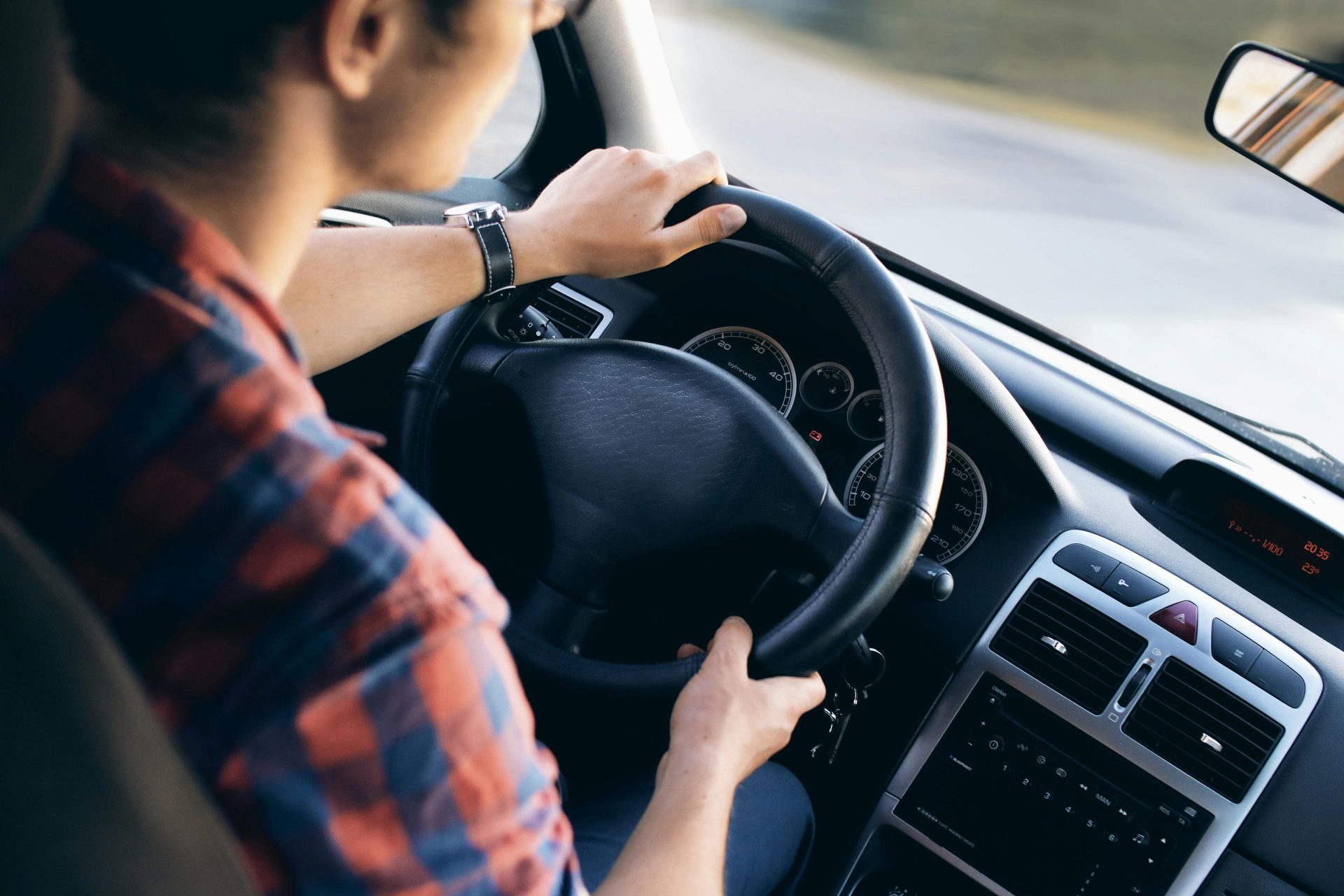 Gros plan sur un homme conduisant une voiture moderne, montrant les détails du tableau de bord et du volant.